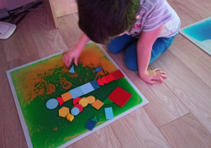 Chłopiec układa obrazki z figur.